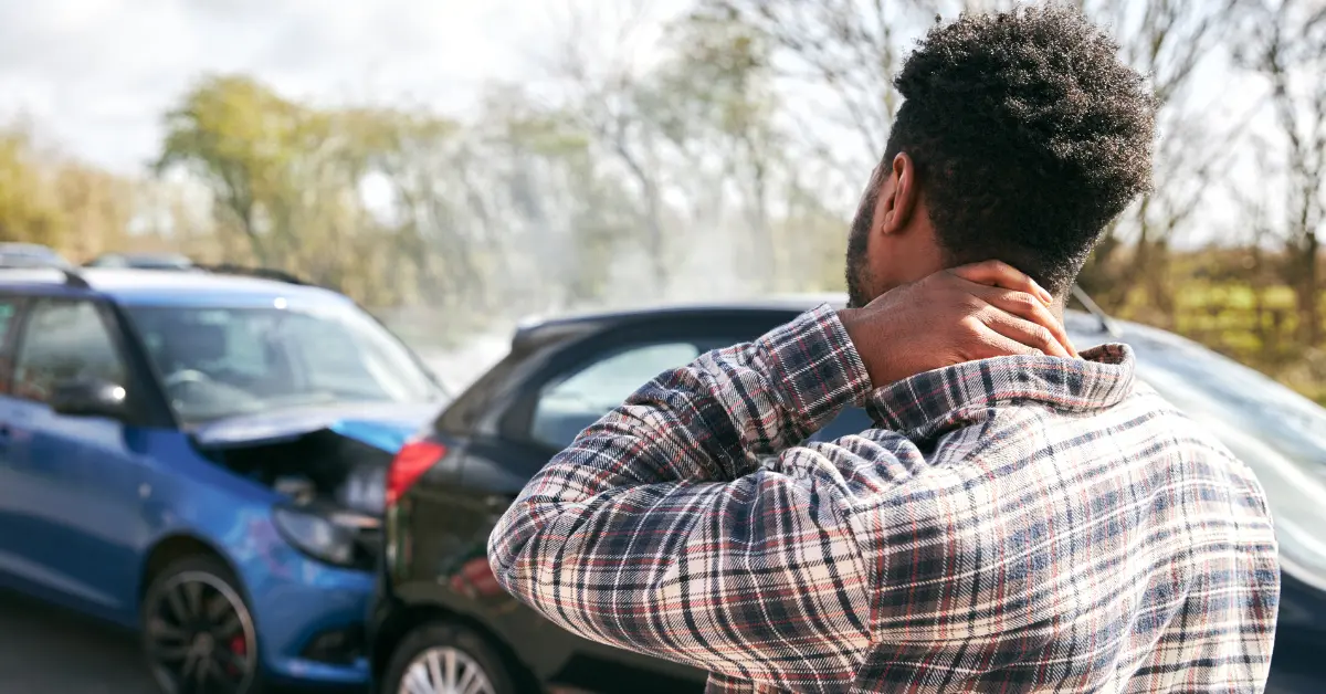 Man rubbing his neck in pain after getting into a car crash.